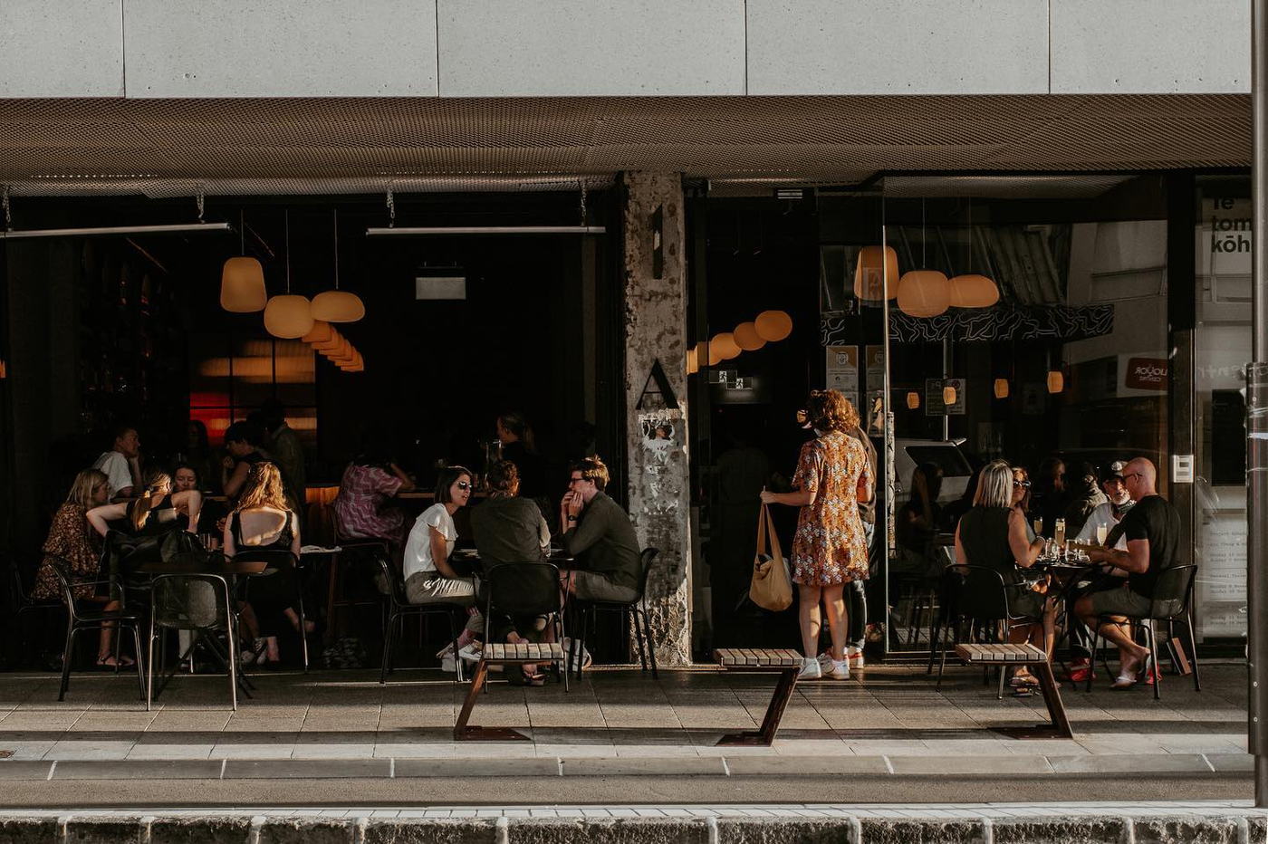 Atelier's street frontage in golden evening light, every outside table full.